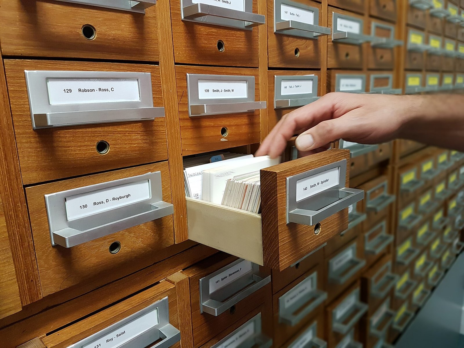 A hand pulling a card from a filing cabinet index